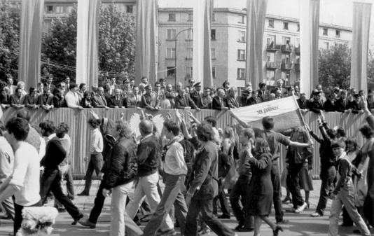 Niezależny pochód pierwszomajowy zorganizowany przez podziemne struktury Solidarności z Wrocławia, wmieszany w pochód oficjalny, maszeruje przed trybuną honorową i pozdrawia gestem zwycięstwa partyjnych notabli.