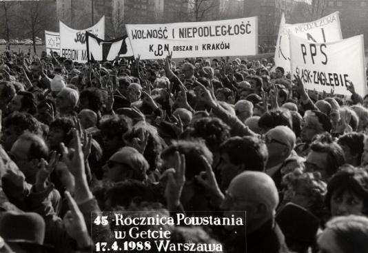 Uczestnicy obchodów 45 rocznicy powstania w getcie warszawskim demonstrują znak V, symbol wolności.
